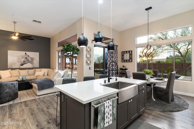 kitchen featuring dishwasher, sink, pendant lighting, dark hardwood / wood-style flooring, and a center island with sink