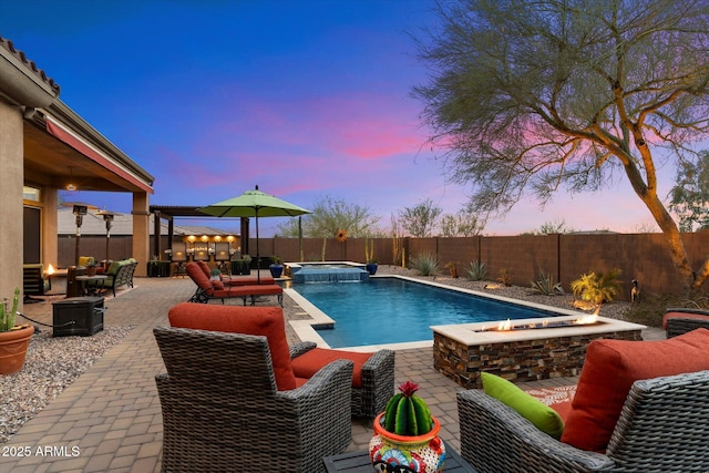 pool at dusk featuring an in ground hot tub, a patio, and an outdoor living space with a fire pit