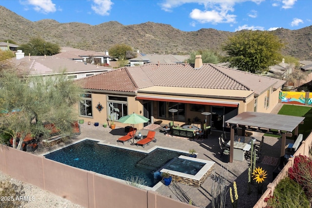 back of property featuring a pool with hot tub, a patio area, outdoor lounge area, and a mountain view