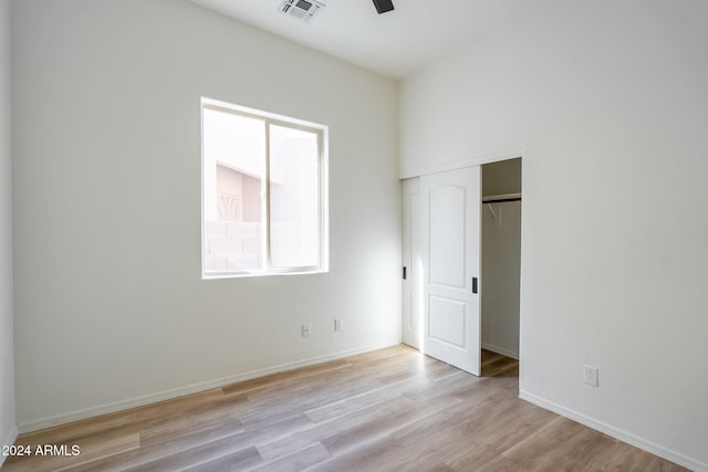 unfurnished bedroom featuring ceiling fan, light hardwood / wood-style floors, and a closet