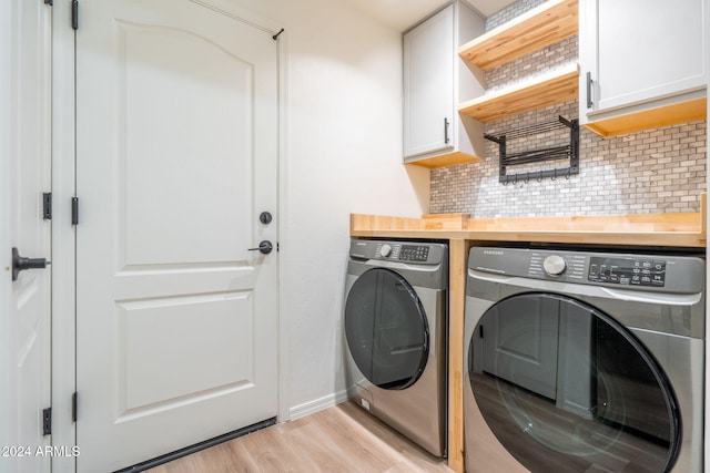 laundry room with washer and clothes dryer, cabinets, and light wood-type flooring