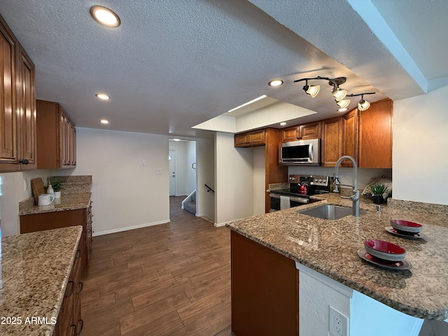 3145 W Acoma Dr, Phoenix, AZ 85053 - kitchen with stainless steel appliances, brown cabinets, stone countertops, dark wood-style flooring, and a textured ceiling