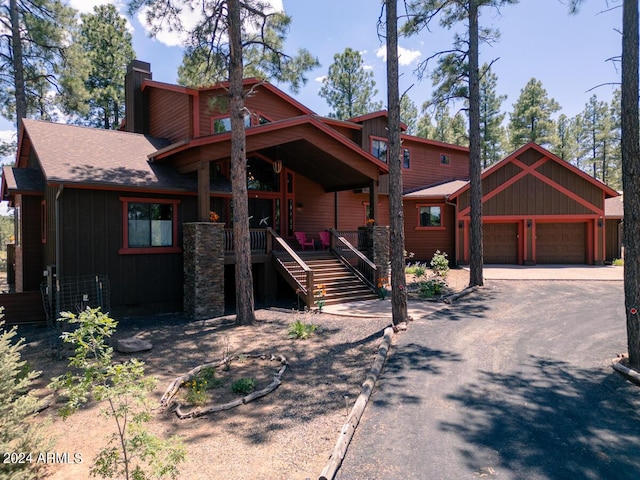 chalet / cabin featuring a chimney, covered porch, driveway, stairway, and a shingled roof
