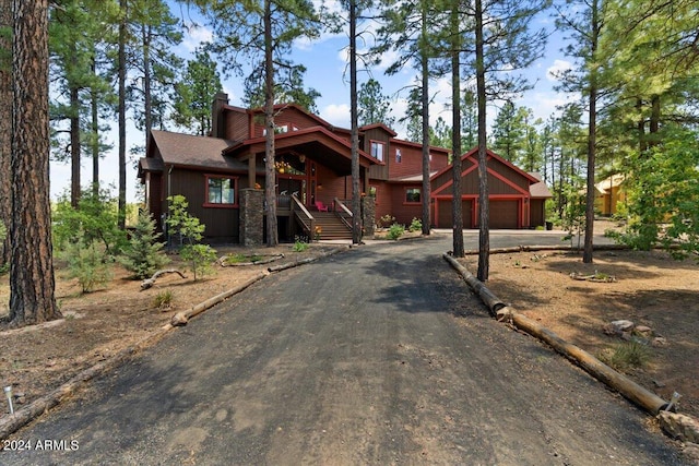 chalet / cabin with an attached garage, driveway, and a chimney
