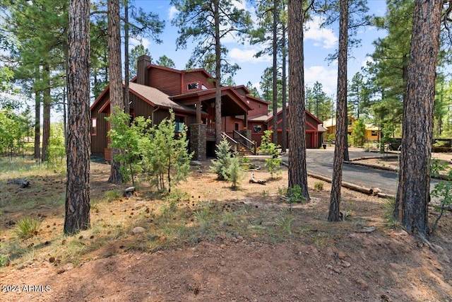 view of front of home with a chimney, asphalt driveway, an attached garage, and stairway