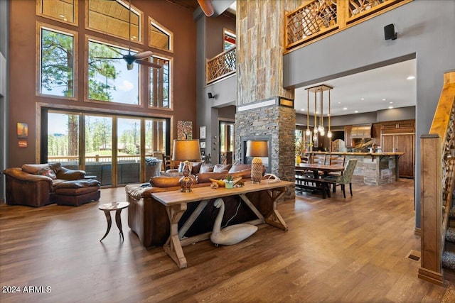 living room with a towering ceiling, wood finished floors, and a ceiling fan