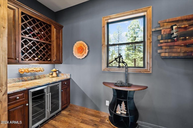 indoor dry bar featuring beverage cooler, dark wood-type flooring, and baseboards