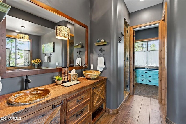 full bath featuring healthy amount of natural light, a shower stall, vanity, and wood finished floors