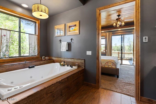 full bath with healthy amount of natural light, ensuite bathroom, a tub with jets, and wood-type flooring