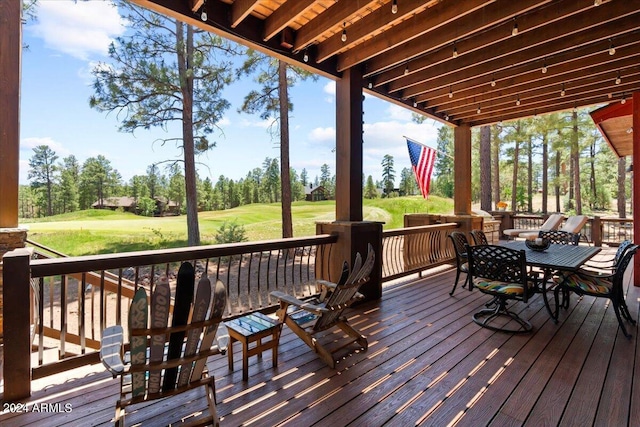 wooden deck with golf course view, view of scattered trees, and a yard