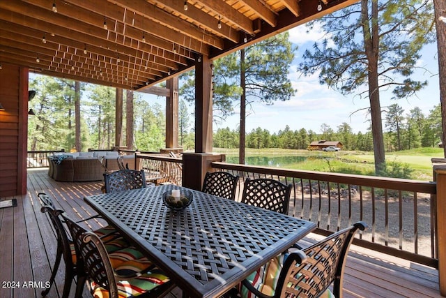 deck with outdoor dining area and view of wooded area