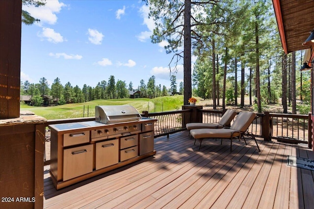 deck featuring exterior kitchen, view of wooded area, and area for grilling