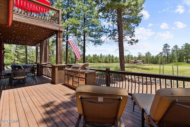 wooden deck featuring view of wooded area and exterior kitchen