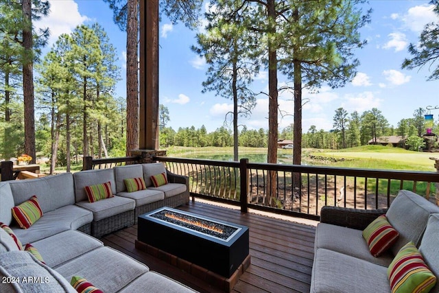 deck featuring an outdoor living space with a fire pit and view of wooded area