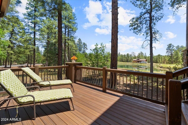 wooden deck with view of scattered trees and a water view
