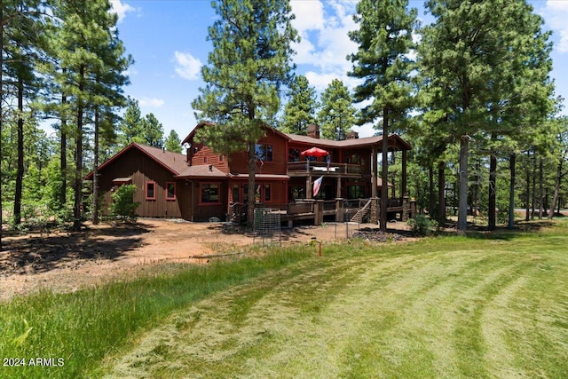 rear view of property featuring a wooden deck, stairway, a chimney, and a lawn