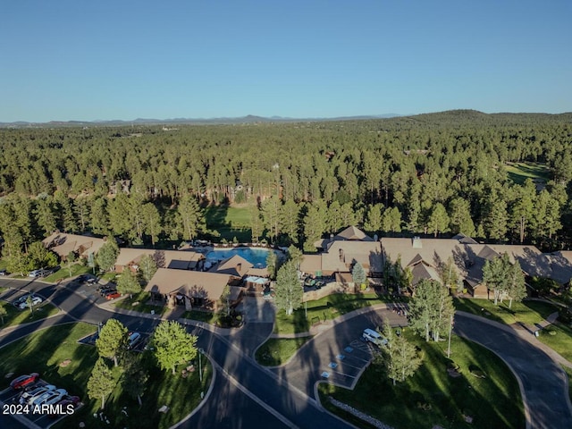 view of property location with a heavily wooded area and a pool area
