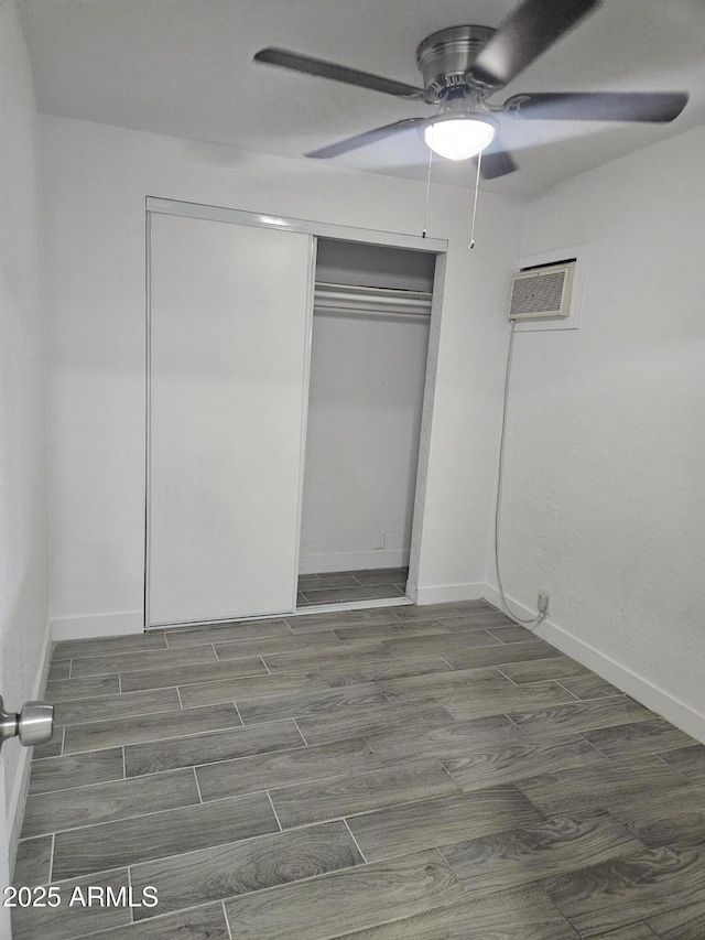 unfurnished bedroom featuring a closet, an AC wall unit, and ceiling fan