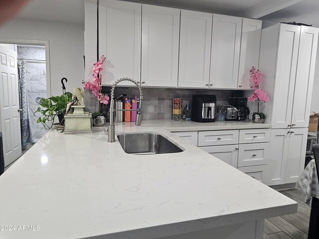 kitchen with tasteful backsplash, light stone countertops, sink, and white cabinets