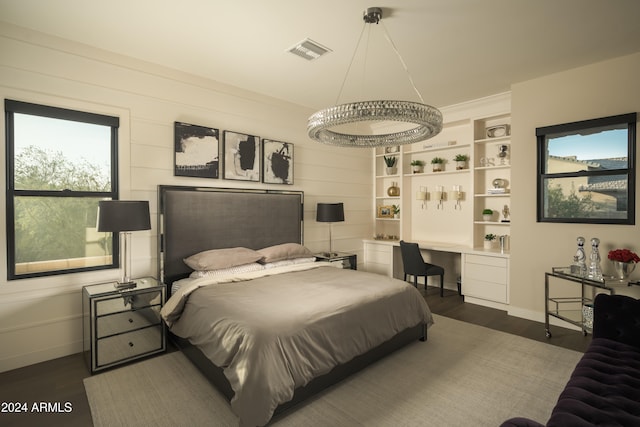 bedroom with dark hardwood / wood-style floors, built in desk, and wooden walls