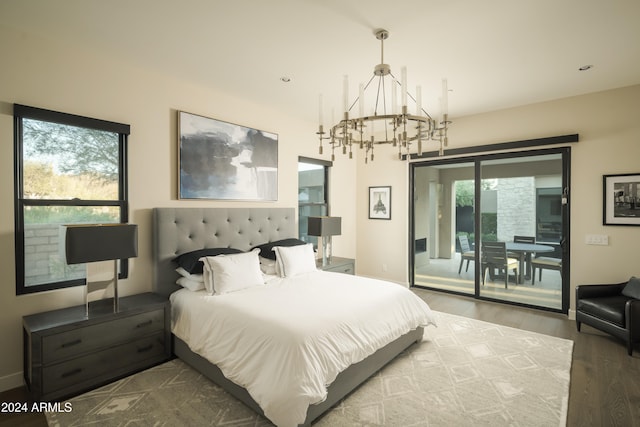 bedroom with access to exterior, wood-type flooring, and an inviting chandelier