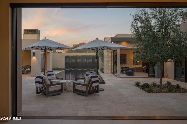 patio terrace at dusk featuring an outdoor living space and a mail area