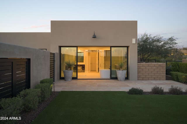 back house at dusk with a yard and a patio