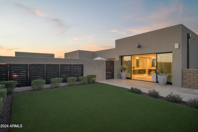 back house at dusk featuring a lawn