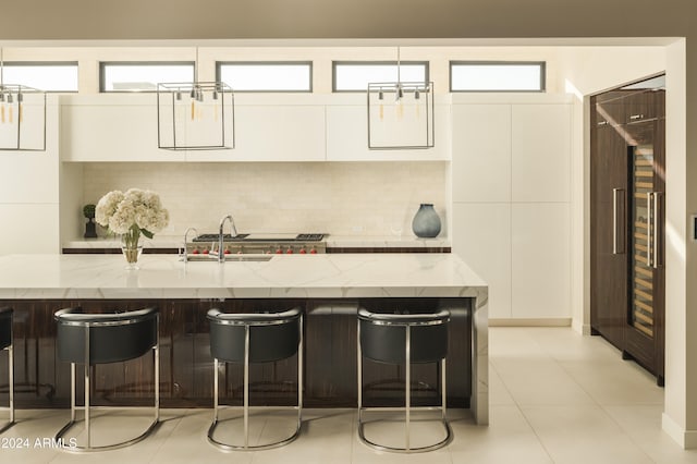 kitchen featuring white cabinetry, a breakfast bar, and light stone counters