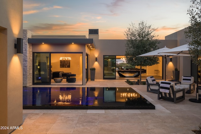 back house at dusk featuring a patio and an outdoor hangout area