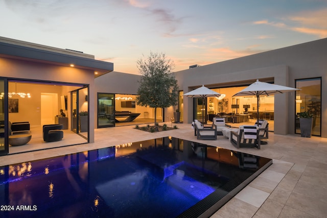 pool at dusk featuring an outdoor living space, a jacuzzi, and a patio