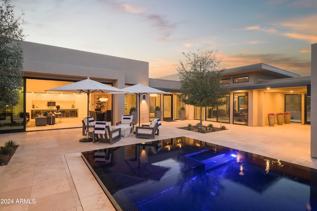 pool at dusk with an in ground hot tub and a patio