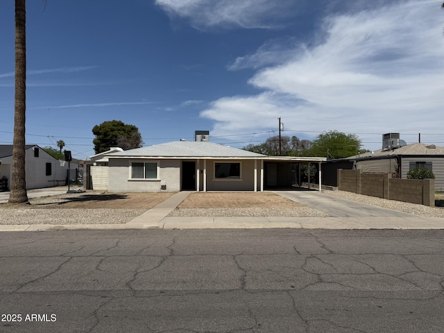 view of front of home with concrete driveway, fence, an attached carport, and stucco siding