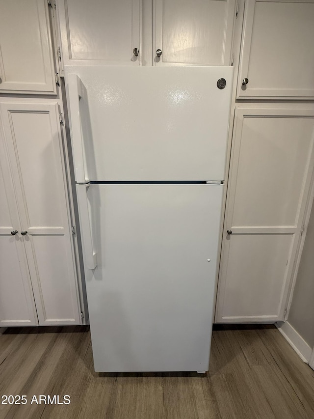 kitchen with white cabinets, freestanding refrigerator, and wood finished floors