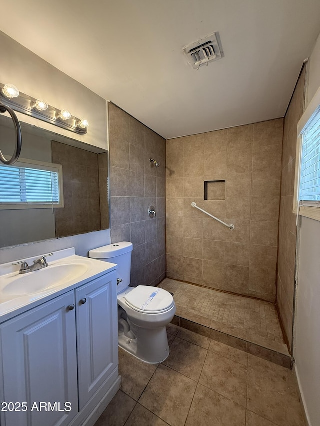 full bathroom with vanity, tile patterned floors, toilet, visible vents, and a tile shower