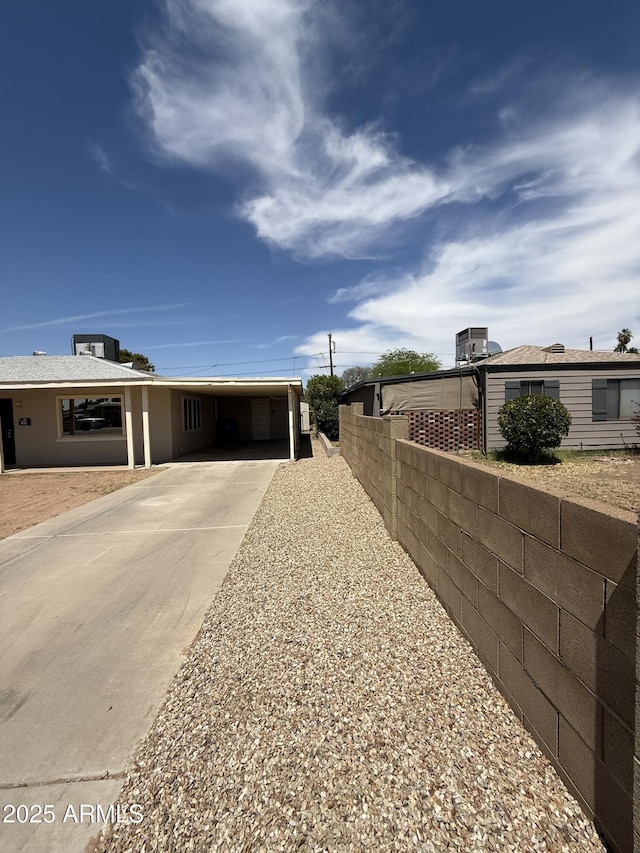 exterior space with an attached carport, driveway, and fence
