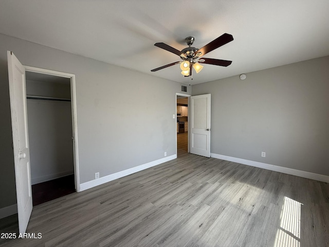 unfurnished bedroom featuring visible vents, baseboards, a closet, a ceiling fan, and wood finished floors