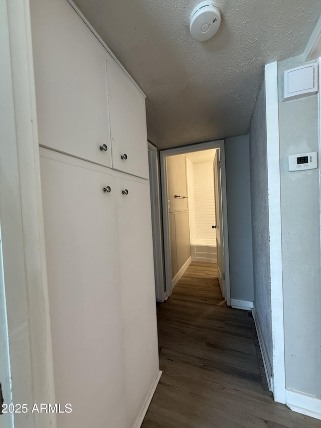 hall with dark wood-style floors, baseboards, and a textured ceiling