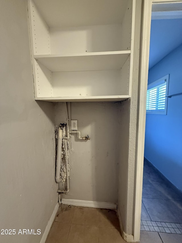 laundry area with tile patterned floors and baseboards