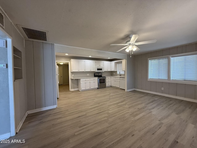 unfurnished living room with visible vents, baseboards, a ceiling fan, and light wood-style flooring