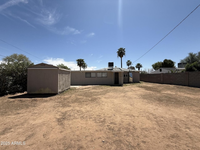 back of house featuring an outbuilding and fence