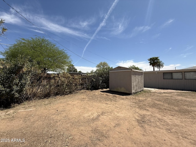view of yard with a storage shed, fence, and an outbuilding