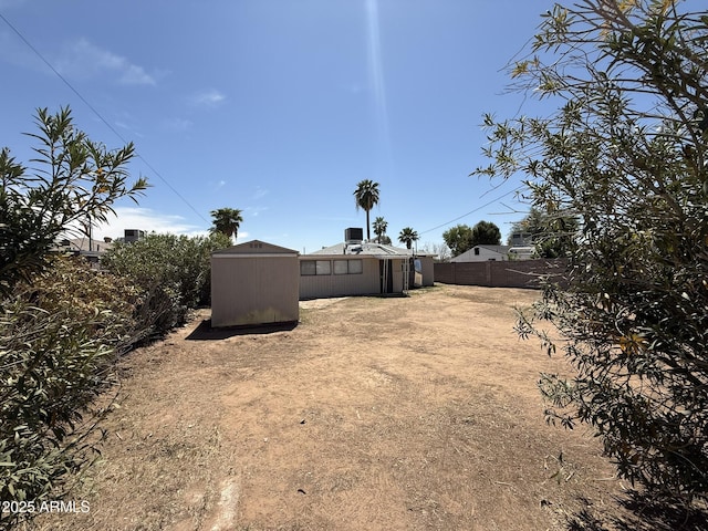 view of yard with an outdoor structure, fence, and a storage unit