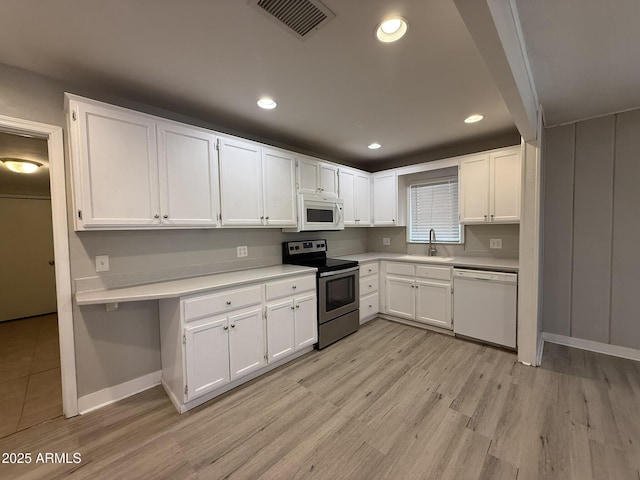 kitchen featuring white appliances, visible vents, light countertops, and a sink