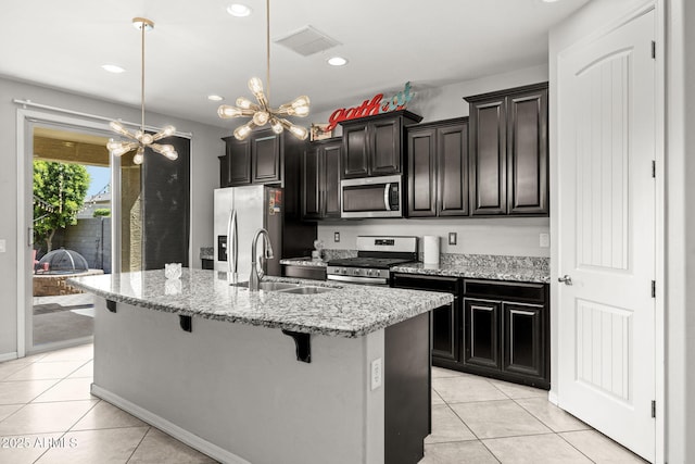 18740 W San Juan Ave, Litchfield Park, AZ 85340 - kitchen with stainless steel appliances, a sink, light tile patterned floors, a kitchen island with sink, and a breakfast bar