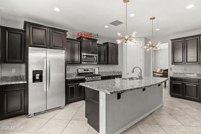 18740 W San Juan Ave, Litchfield Park, AZ 85340 - kitchen with stainless steel appliances, a sink, light tile patterned floors, light stone counters, and a breakfast bar