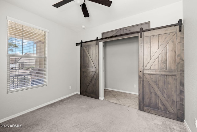 18740 W San Juan Ave, Litchfield Park, AZ 85340 - unfurnished bedroom featuring a barn door, carpet floors, ceiling fan, and baseboards