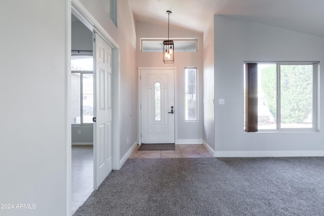 foyer featuring lofted ceiling, light tile patterned floors, baseboards, and light colored carpet