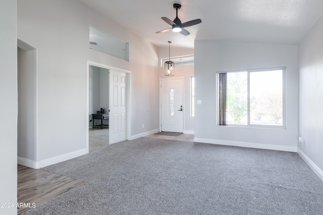 interior space with baseboards, ceiling fan, high vaulted ceiling, and light colored carpet