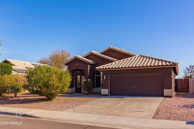 mediterranean / spanish-style home with concrete driveway, an attached garage, a tile roof, and stucco siding